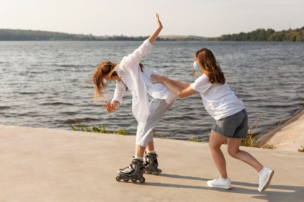 Vue latérale d'amis s'amusant au bord du lac avec des patins à roulettes
