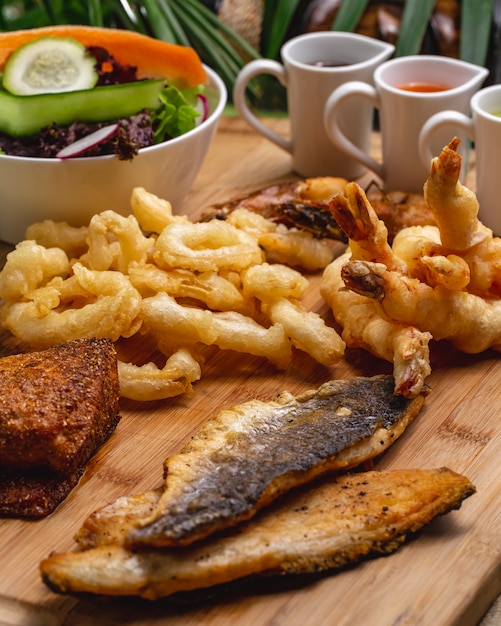 Photo gratuite vue latérale apéritifs de fruits de mer crevettes de calmar de poisson avec sauces et salade