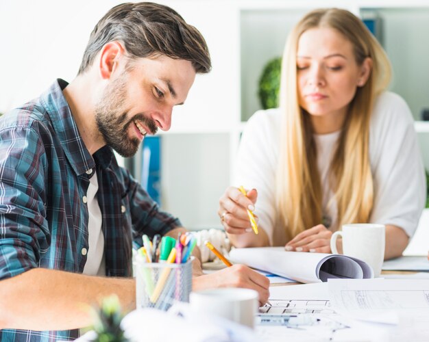 Vue latérale d&#39;un architecte mâle heureux travaillant sur blueprint