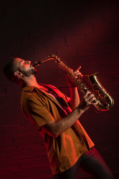 Vue latérale de l'artiste masculin jouant du saxophone