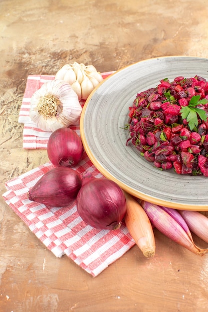 Photo gratuite vue latérale de l'assiette d'une salade rouge avec des verts dessus sur un backgorund en bois