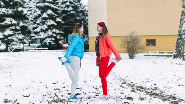 Vue latérale d&#39;athlète féminine qui s&#39;étend de la jambe en hiver