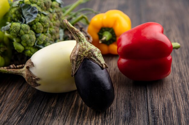 Vue latérale de l'aubergine avec des poivrons de couleur brocoli et oignons verts sur fond de bois