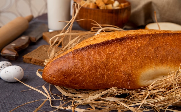 Vue latérale de la baguette sur la paille avec l'oeuf sur fond marron