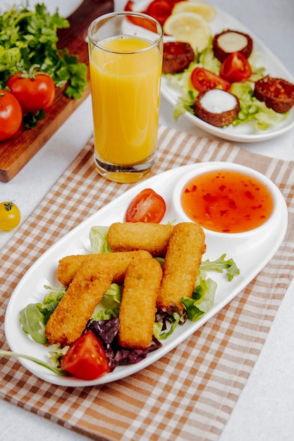 Vue latérale de bâtonnets de fromage frit avec sauce