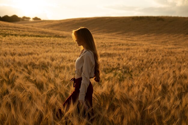 Vue latérale belle femme posant au coucher du soleil