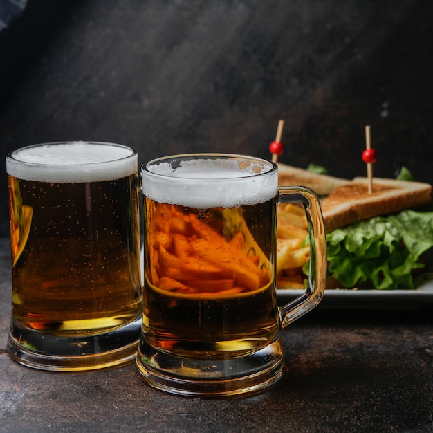 Vue latérale de la bière avec une assiette de sandwich et de pommes de terre frites