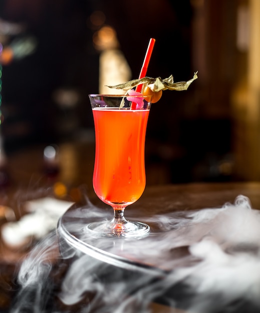 Vue latérale boisson aux fruits avec physalis et paille dans le verre