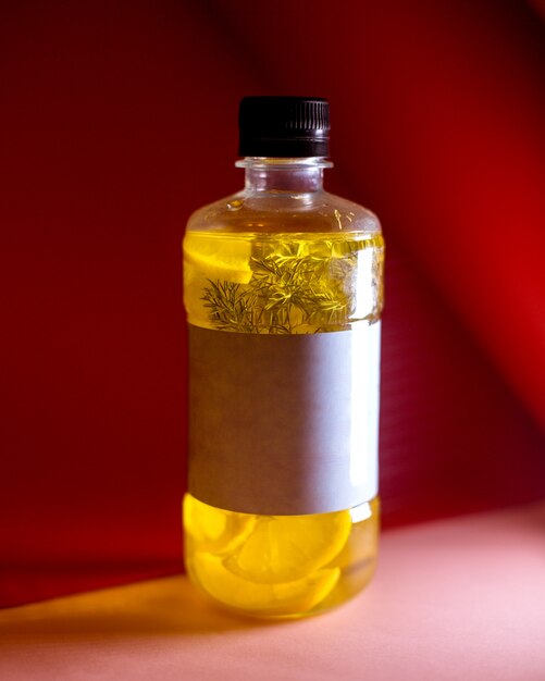 Vue latérale d'une boisson détox au citron dans une bouteille sur jaune foncé