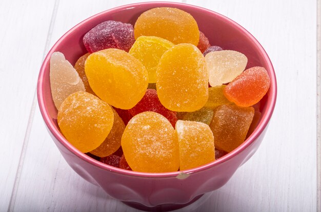 Vue latérale de bonbons colorés délicieux marmelade dans un bol sur rustique