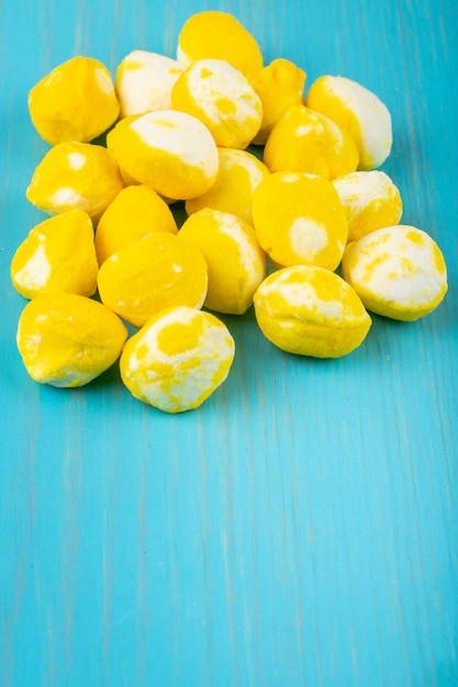 Photo gratuite vue latérale des bonbons sucrés jaunes sur fond de bois bleu avec copie espace