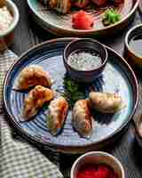Photo gratuite vue latérale des boulettes asiatiques traditionnelles avec de la viande et des légumes servis avec de la sauce soja sur une assiette sur rustique
