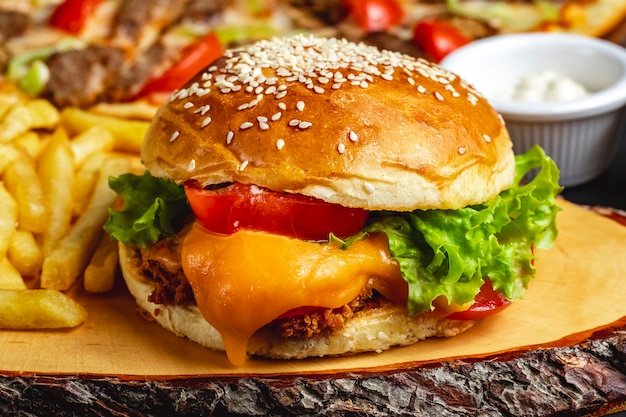 Vue latérale burger de poulet filet de poulet cuit en profondeur avec du fromage à la tomate et de la laitue entre les pains à burger