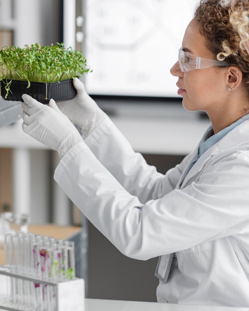 Photo gratuite vue latérale d'une chercheuse en laboratoire avec des lunettes de sécurité et des plantes