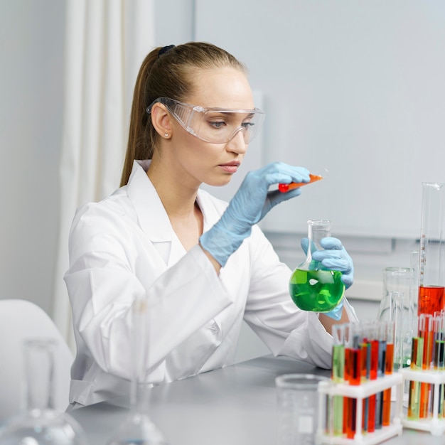 Photo gratuite vue latérale de la chercheuse en laboratoire avec des tubes à essai