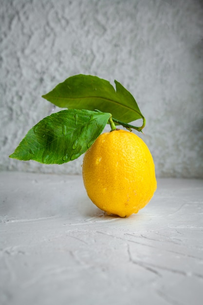 Vue Latérale Citron Avec Des Feuilles Sur Fond Texturé Blanc. Espace Vertical Pour Le Texte