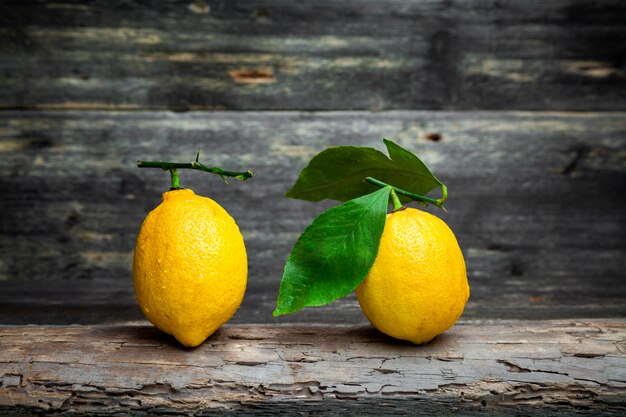 Vue latérale des citrons avec et sans feuilles sur fond de bois foncé. horizontal