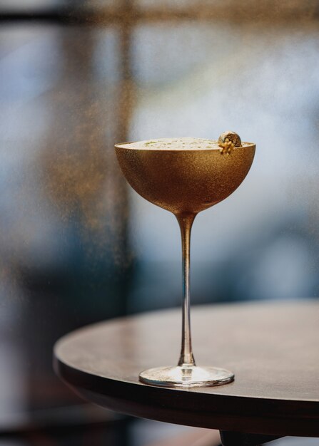 Vue latérale d'un cocktail d'alcool avec du kiwi dans un verre doré sur une table en bois