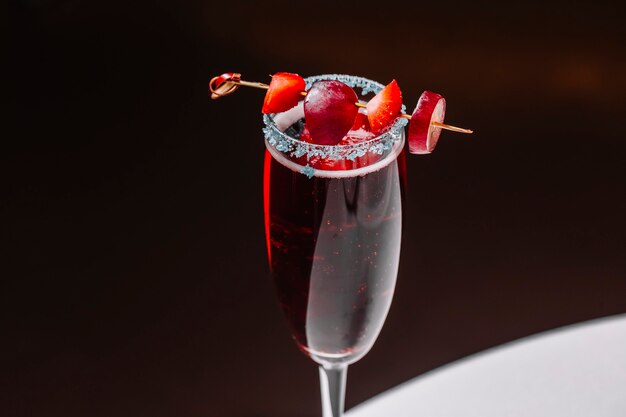 Vue latérale cocktail martini avec fraise et raisin dans un verre de champagne