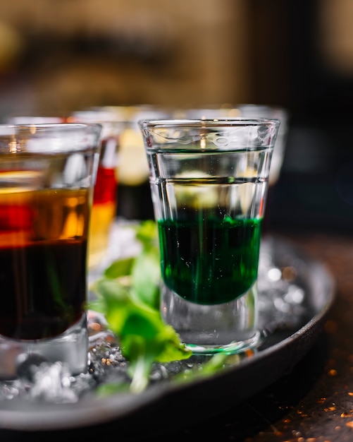 Vue latérale de cocktails colorés dans des verres à liqueur