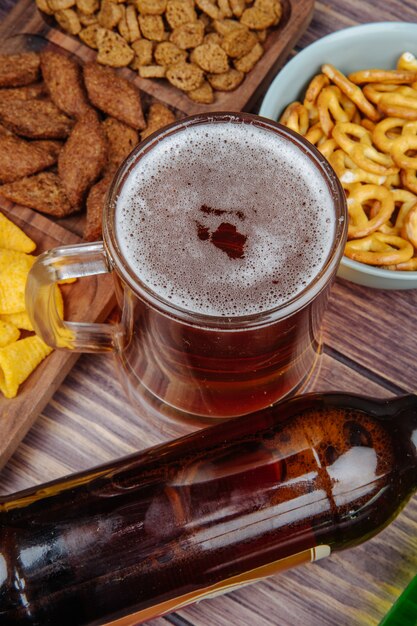 Vue latérale de collations de bière variées biscuits au pain chips et mini bretzels avec une chope de bière sur rustique