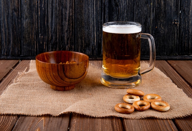 Photo gratuite vue latérale collations pour chuck dur de bière dans un bol et des craquelins avec chope de bière sur table en bois