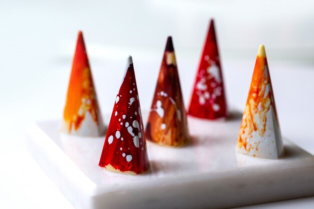 Vue latérale conique multicolore dans un bonbon au chocolat blanc sur socle blanc