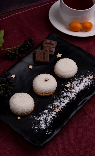 Vue latérale des cookies avec des flocons de noix de coco et des morceaux de chocolat sur un tableau noir