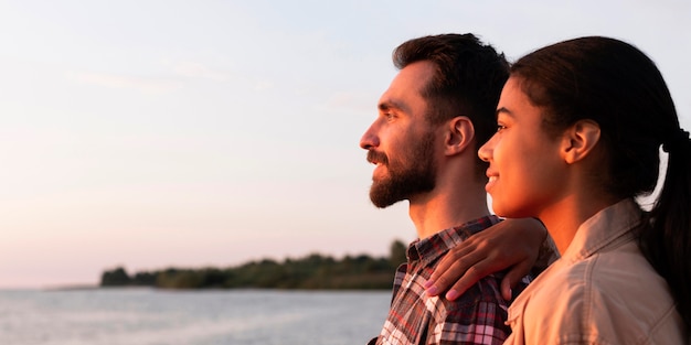 Photo gratuite vue latérale couple profitant du coucher de soleil avec espace copie