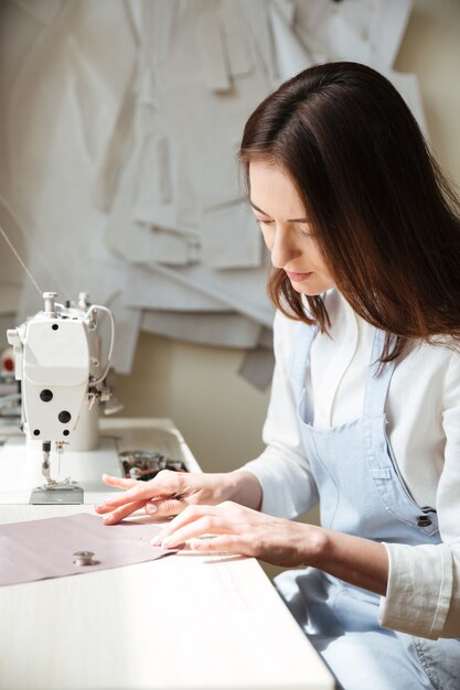 Vue latérale d'une couturière travaillant avec une machine à coudre