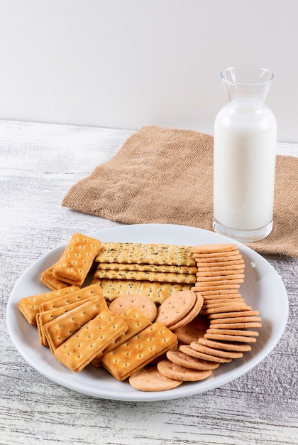 Vue latérale des craquelins avec du lait sur une table en bois blanc