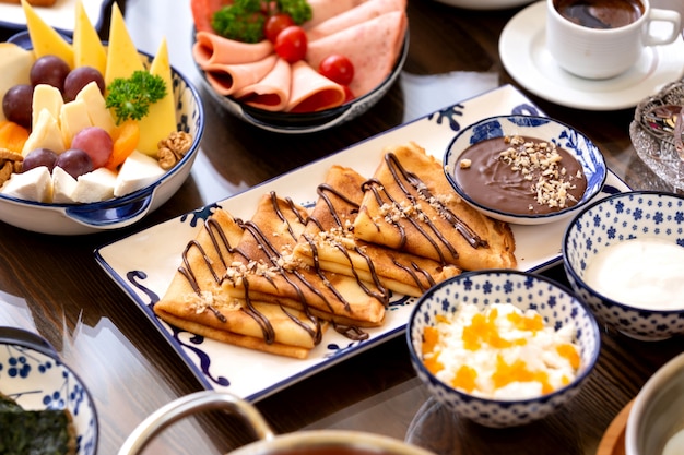 Photo gratuite vue latérale des crêpes avec de la crème au chocolat et des noix sur le plateau