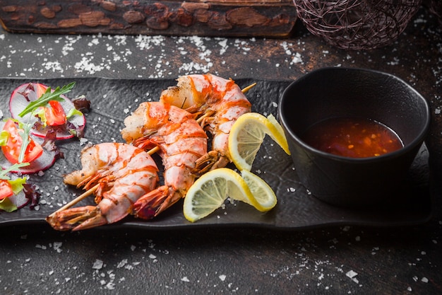 Vue latérale des crevettes frites avec sauce épicée et tranches de citron