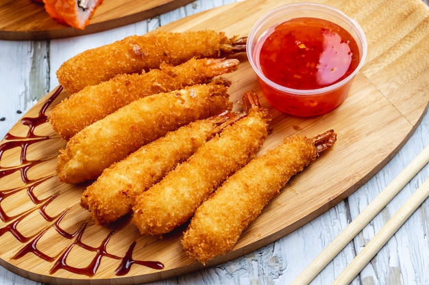 Vue latérale des crevettes tempura avec sauce chili douce sur une planche