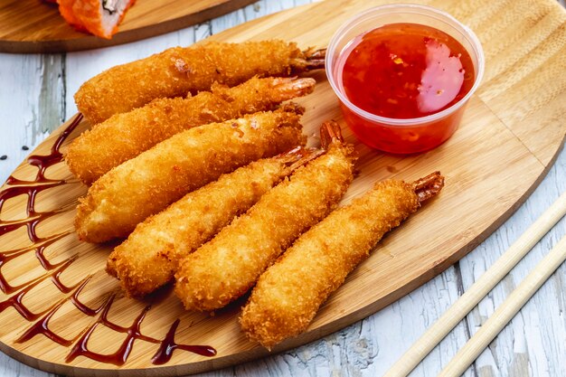 Vue latérale des crevettes tempura avec sauce chili douce sur une planche