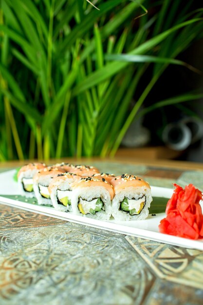 Vue latérale de la cuisine japonaise traditionnelle sushi philadelphia roll avec saumon fromage philadelphia concombre avocat sur vert