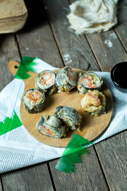 Vue latérale de la cuisine traditionnelle japonaise sushi tempura maki servi avec du gingembre et de la sauce de soja sur planche de bois