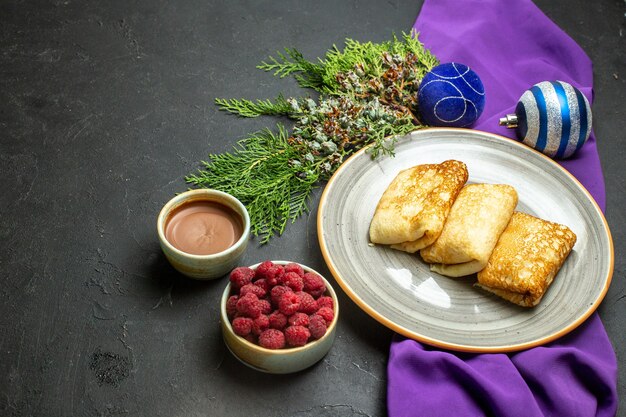 Vue Latérale De Délicieux Accessoires De Décoration De Crêpes Sur Serviette Violette Et Framboise Au Chocolat Sur Fond Noir