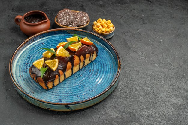 Vue latérale de délicieux gâteaux sur plateau bleu et biscuits sur table sombre