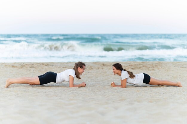 Photo gratuite vue latérale de deux amies exerçant sur la plage