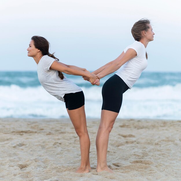 Vue latérale de deux femmes qui s'étendent sur la plage