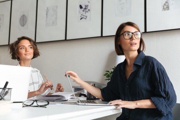 Vue latérale de deux jolies femmes assises près de la table