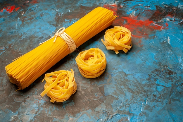 Vue latérale de diverses pâtes italiennes pour la préparation du dîner sur le côté droit sur fond bleu