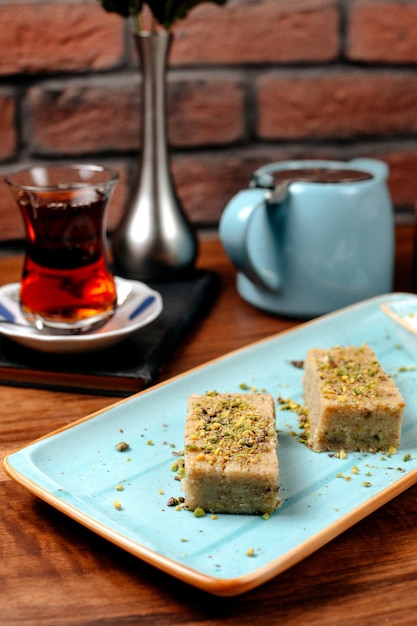 Vue latérale du baklava de bonbons turcs à la pistache servi avec de la crème glacée sur le plateau