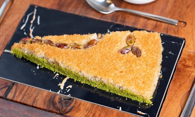 Vue latérale du baklava turc avec pistache sur une planche de bois