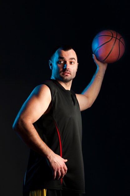 Vue latérale du basketteur avec ballon dans une main