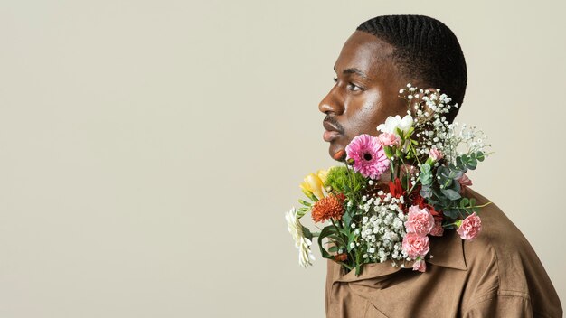 Vue latérale du bel homme posant avec bouquet de fleurs et espace copie