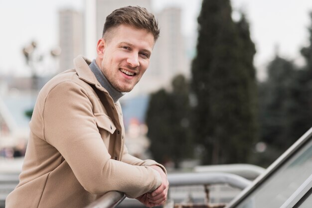 Vue latérale du bel homme souriant à l'extérieur