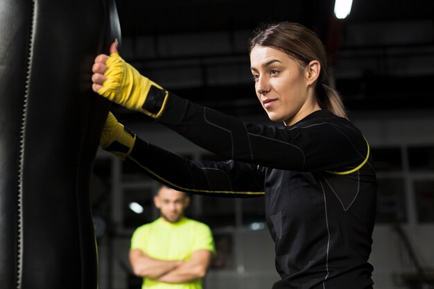 Vue latérale du boxeur féminin avec entraîneur défocalisé