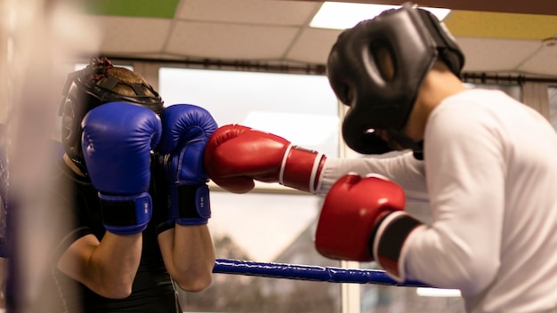 Vue latérale du boxeur masculin avec casque pratiquant dans le ring